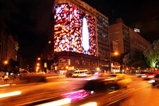Cartel LED robótico Coca-Cola de noche con tráfico — Prina