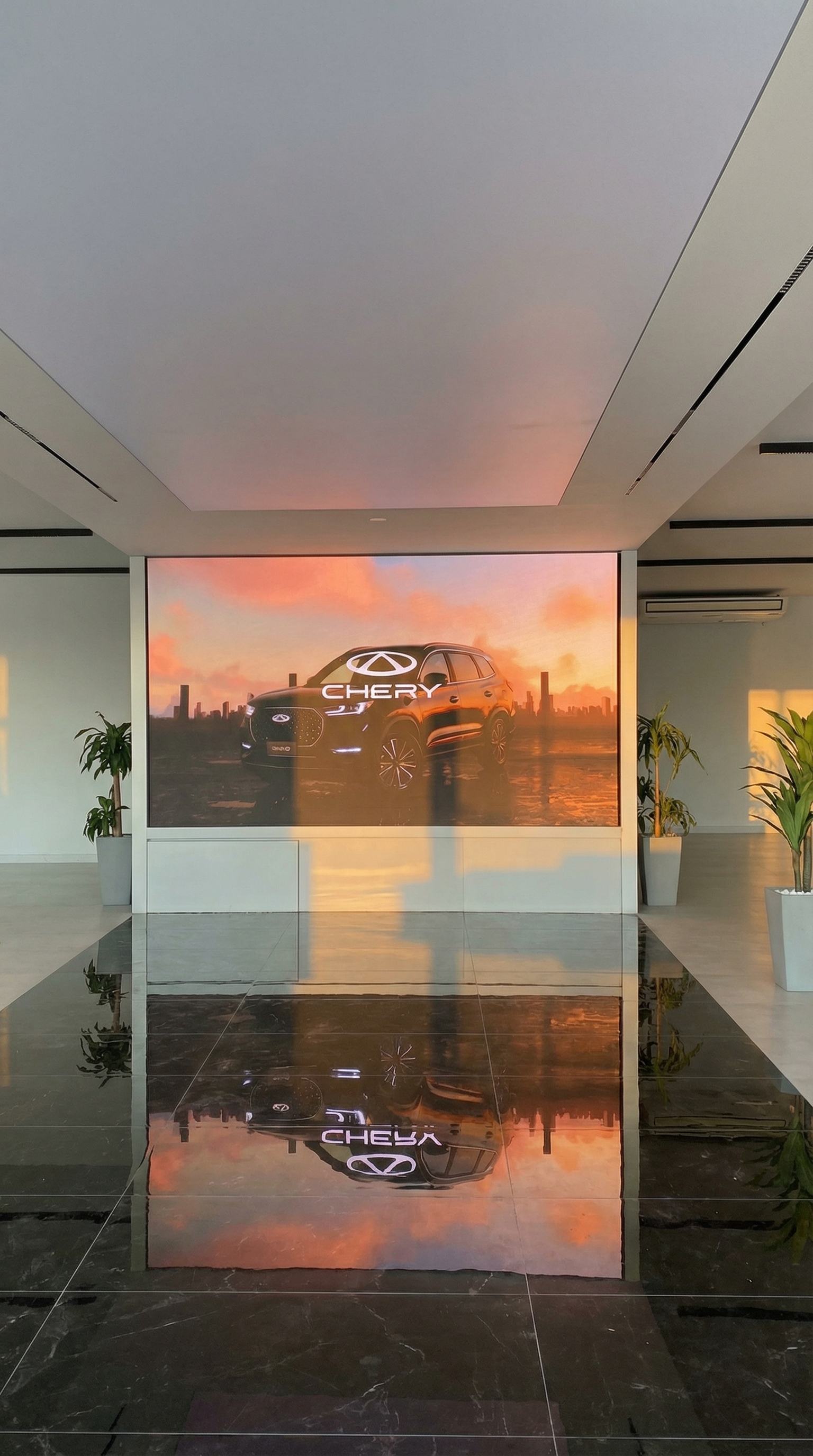 Pantalla LED de gran formato en concesionario Chery mostrando un SUV al atardecer