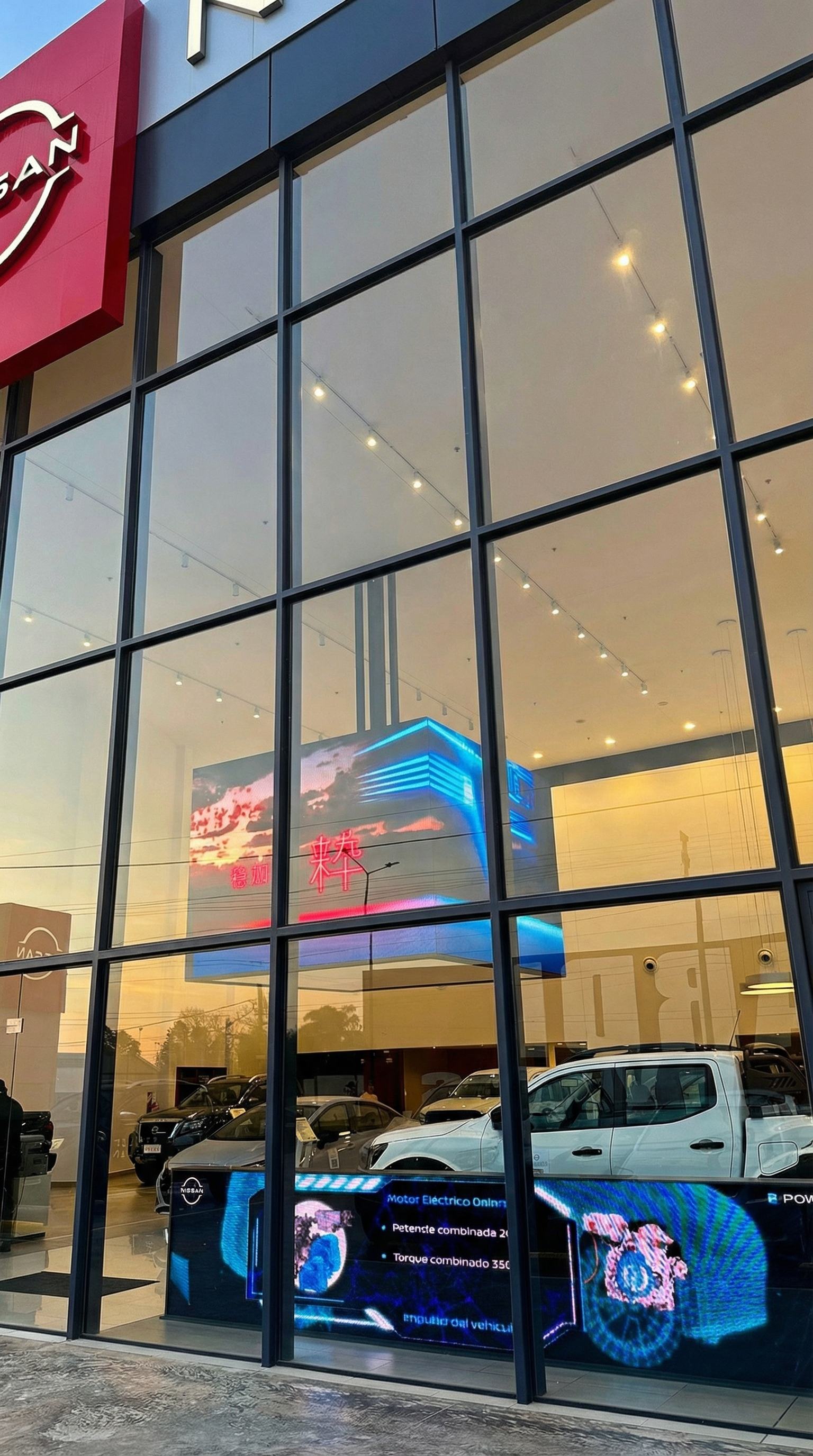 Concesionario Nissan de noche con pantallas LED visibles a través del vidrio
