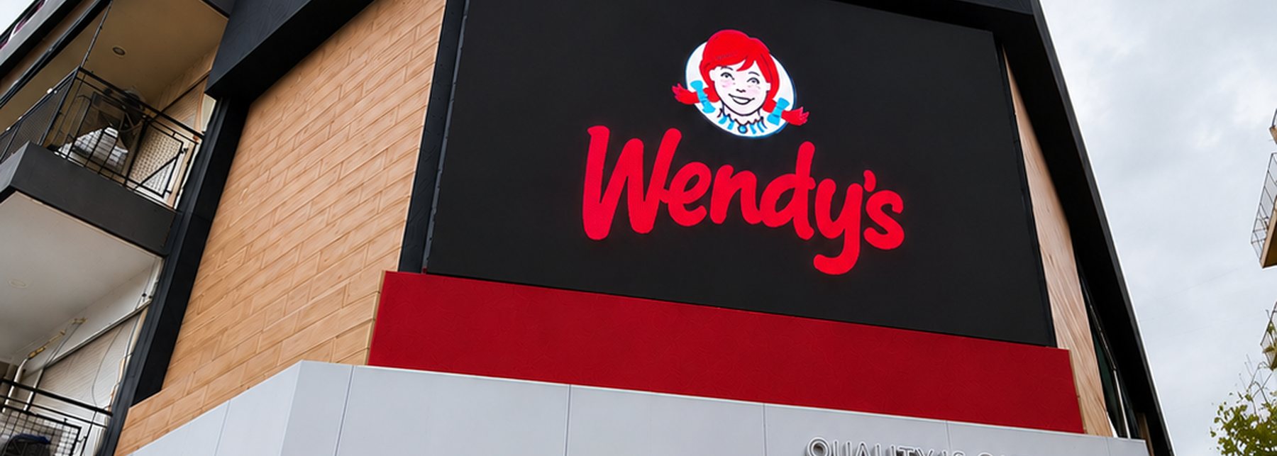 Pantalla LED integrada a la fachada de un local de Wendy's, mostrando el logo de la marca